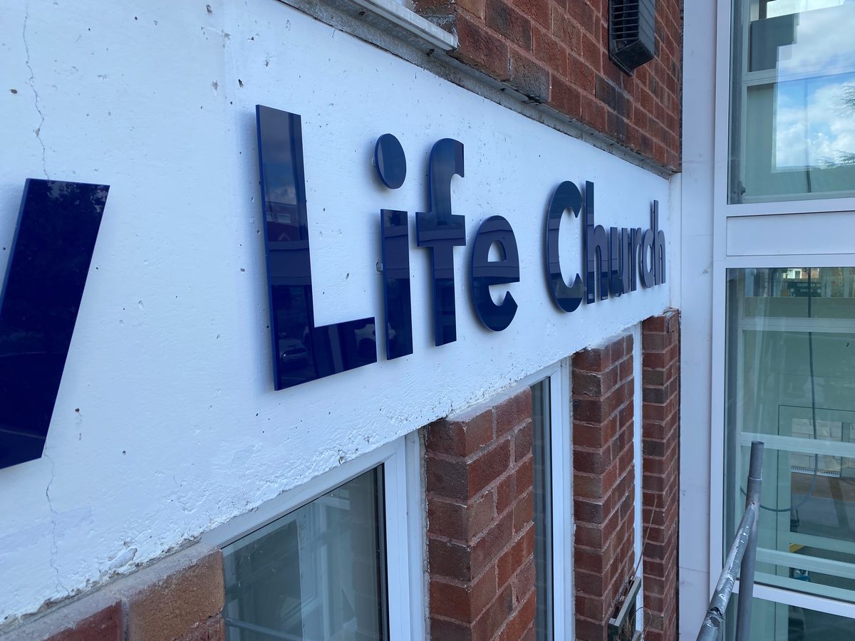 Navy acrylic 'Life Church' letters on a white fascia above brickwork and windows