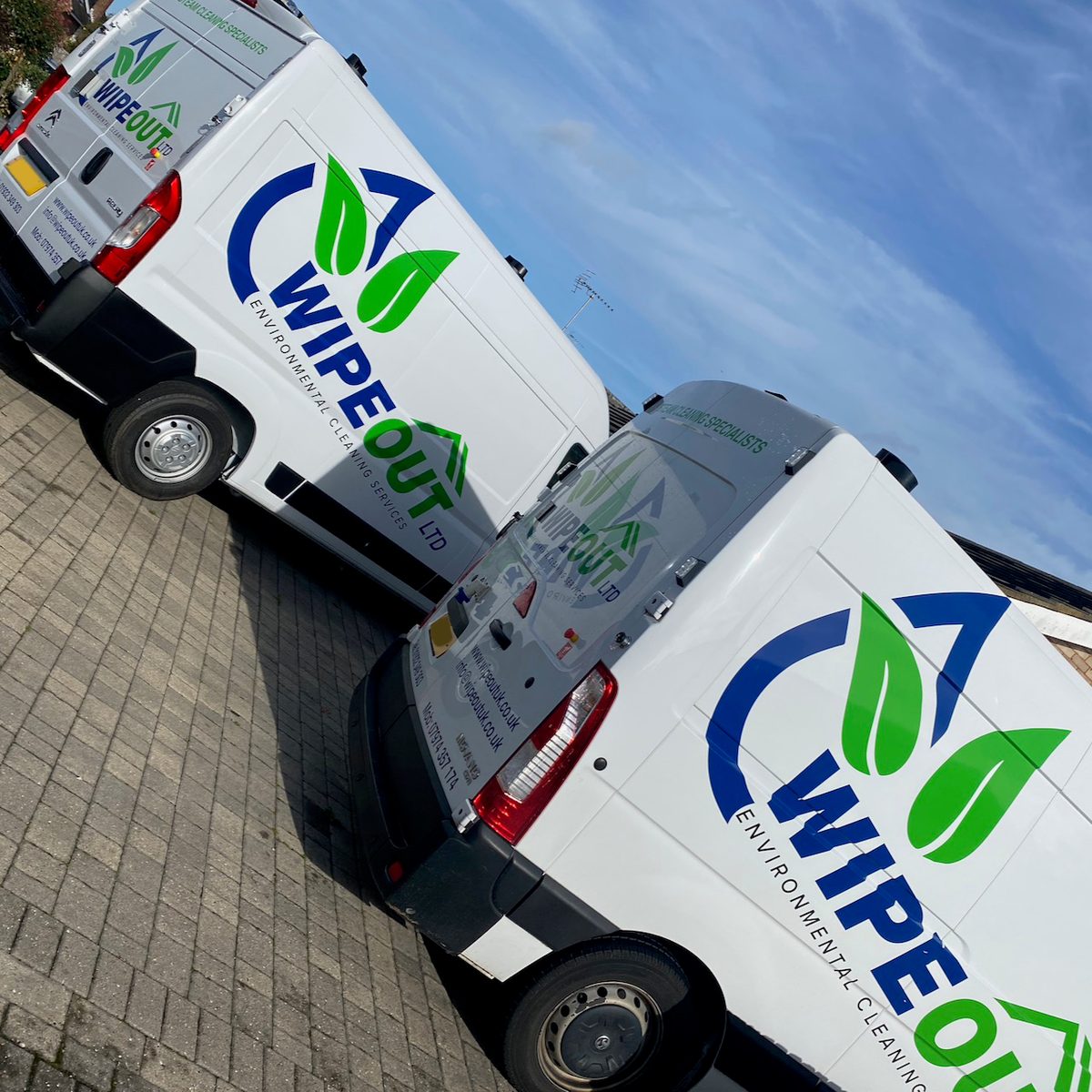 Two white vans with blue and green Wipeout Environmental Cleaning Services logos