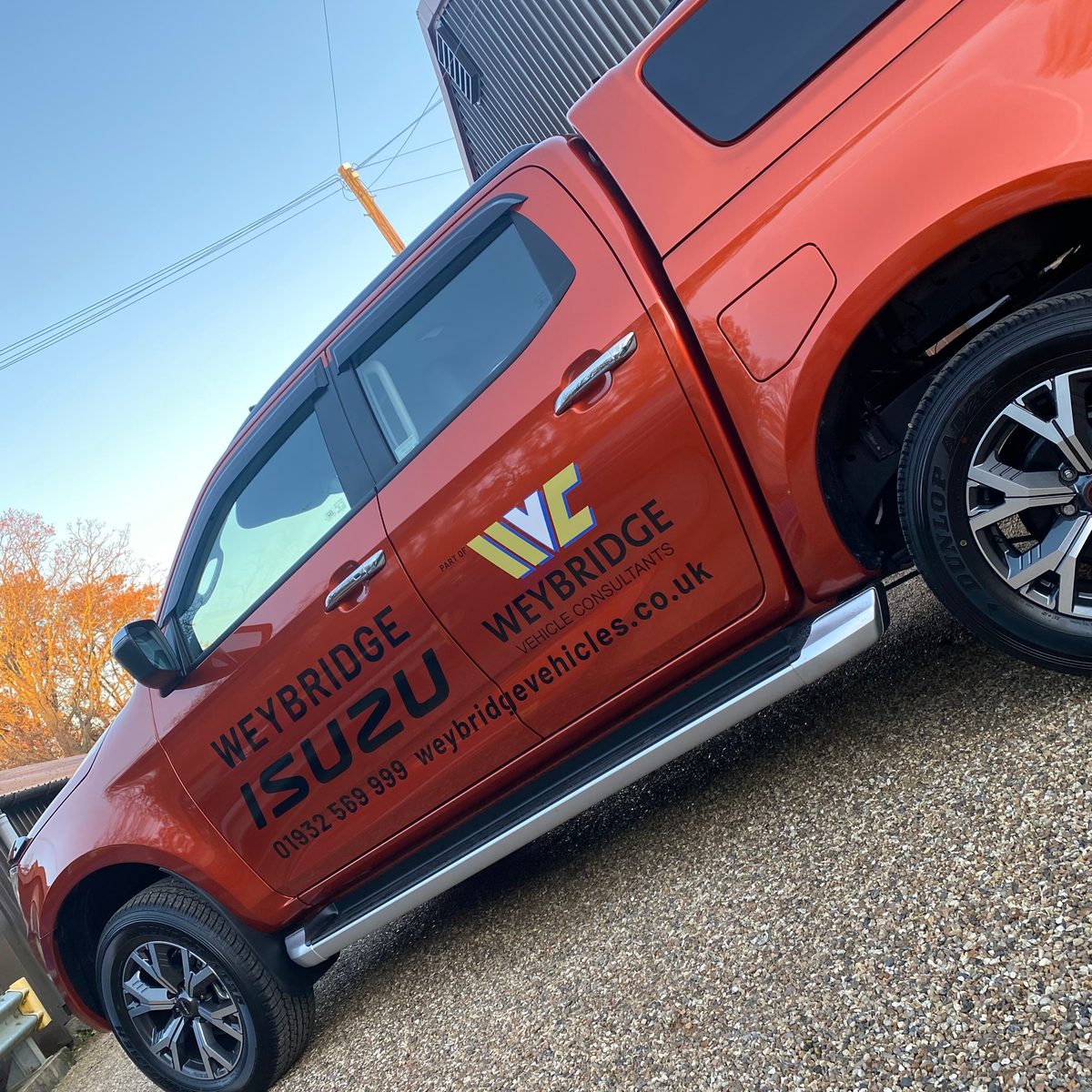 Orange Isuzu pickup with Weybridge Vehicle Consultants lettering and web address on doors