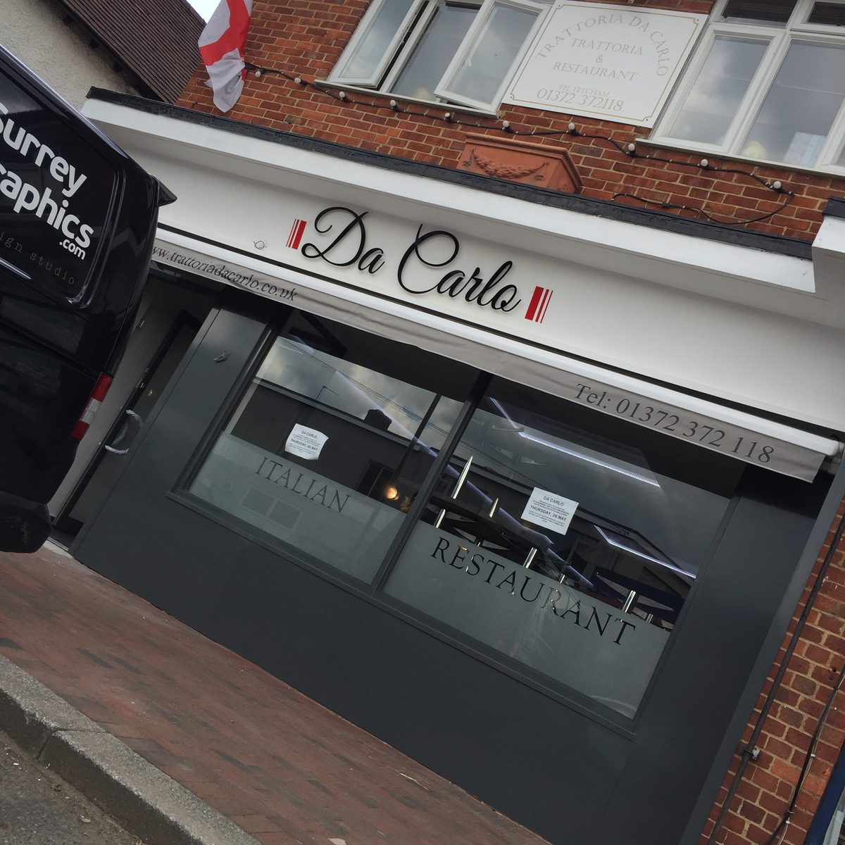 Black script 'Da Carlo' letters on a white fascia above an Italian restaurant window