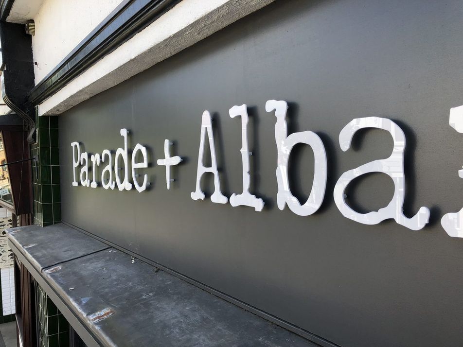 Close-up of white 3D 'Parade + Albany' letters on a dark grey shopfront fascia