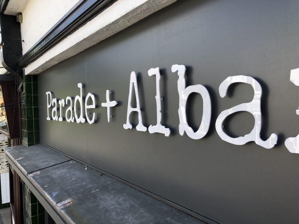 Close-up of white 3D 'Parade + Albany' letters on a dark grey shopfront fascia