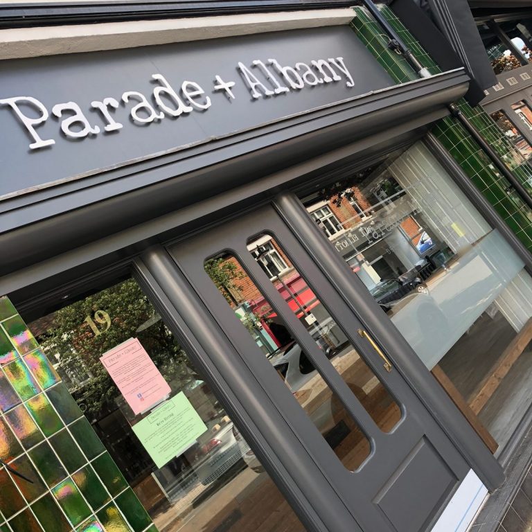 Parade + Albany shopfront with white 3D lettering on a grey fascia above green-tiled windows