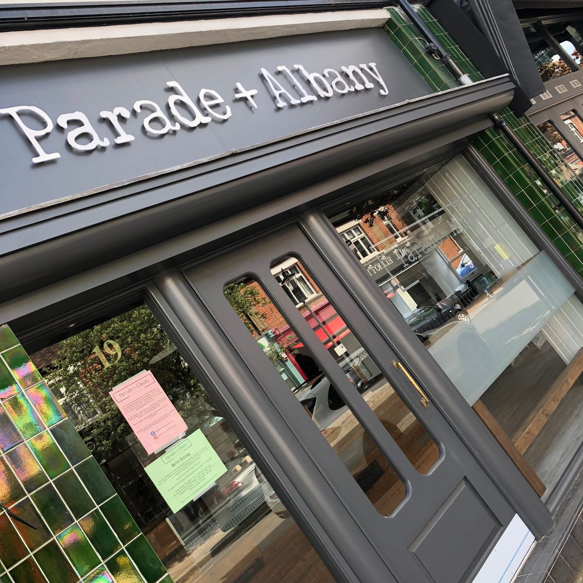 Parade + Albany shopfront with white 3D lettering on a grey fascia above green-tiled windows