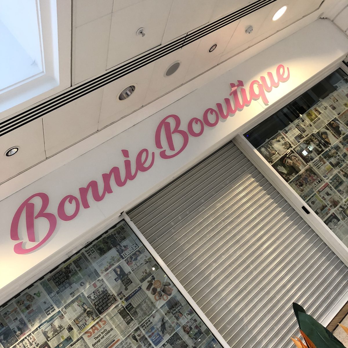 Pink script 'Bonnie Boutique' 3D letters on a white fascia above a shuttered shopfront