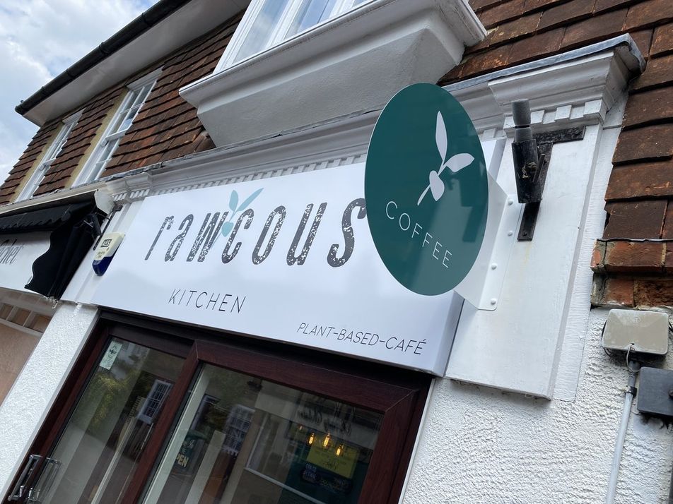 White Rawcous Kitchen plant-based café fascia sign with a round green Coffee projecting sign