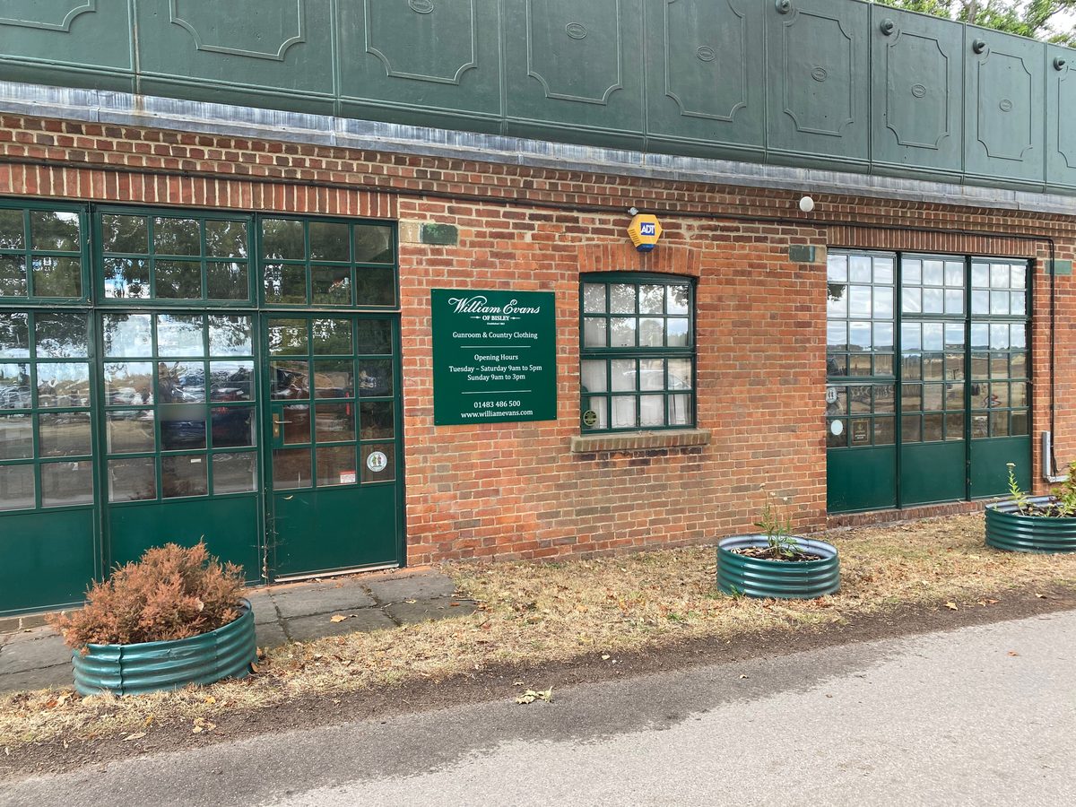 Green William Evans of Bisley gunroom and opening hours sign on a brick building with green windows