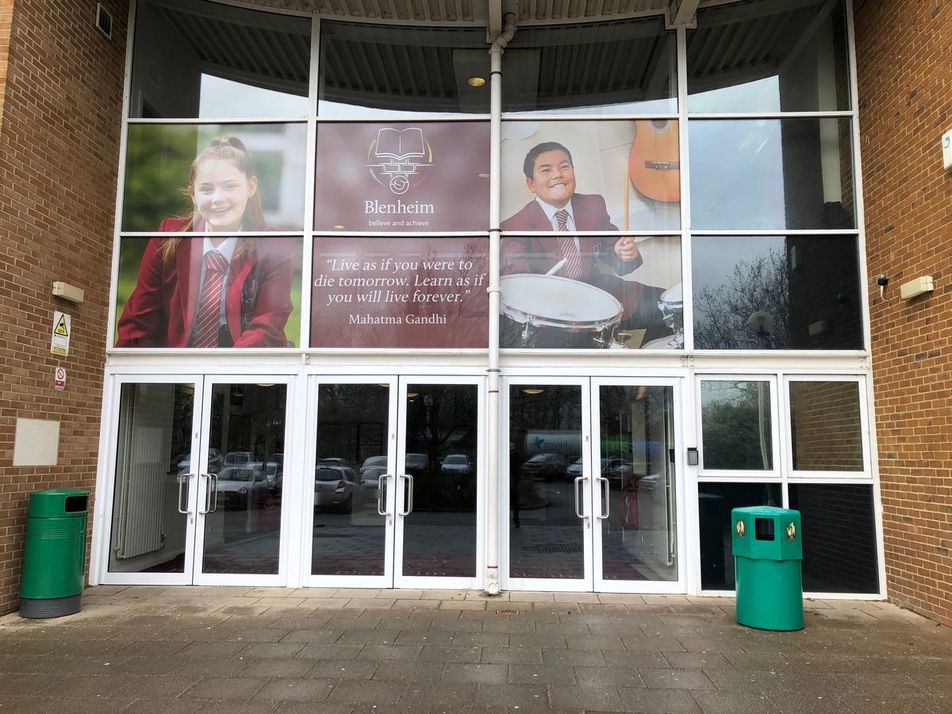School entrance glazing with printed one-way vision graphics of Blenheim pupils, crest and quotation