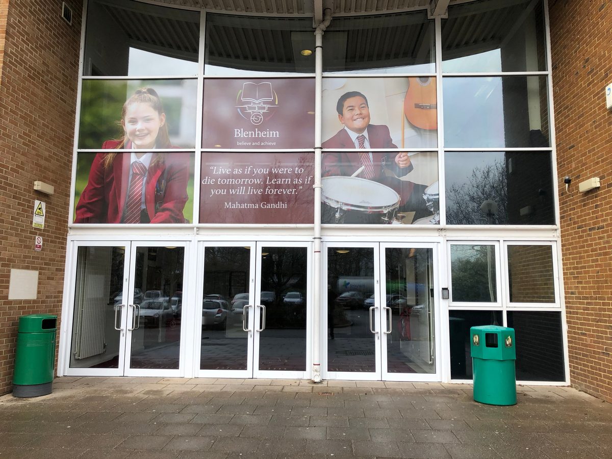 School entrance glazing with printed one-way vision graphics of Blenheim pupils, crest and quotation