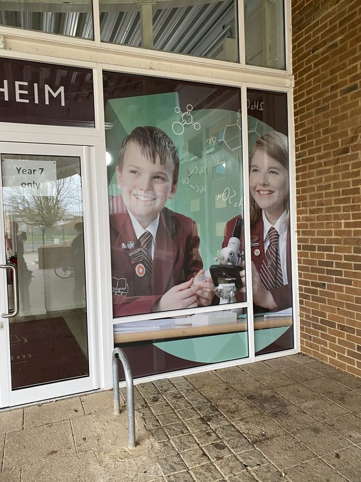 Blenheim school window with printed one-way vision graphic of two pupils using a microscope