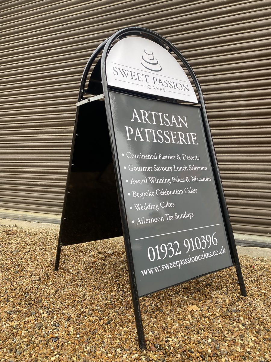 Black metal A-board pavement sign for Sweet Passion Cakes Artisan Patisserie, with services and phone number